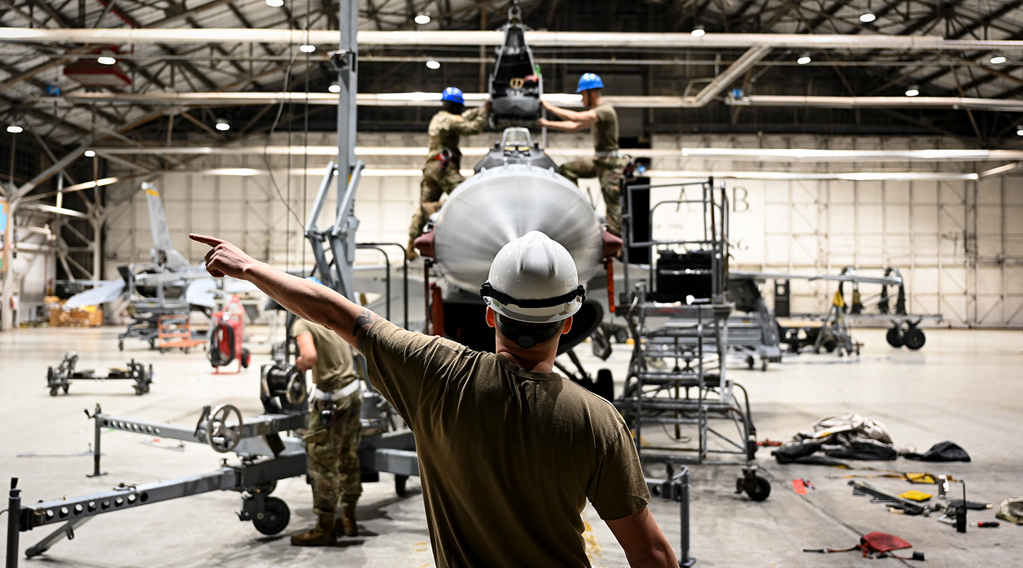 airman directing two other airmen to perform a precise coordination of aircraft seats