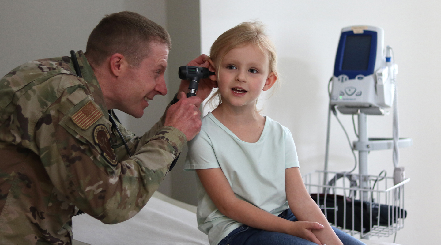 airman inspecting toddler's ear