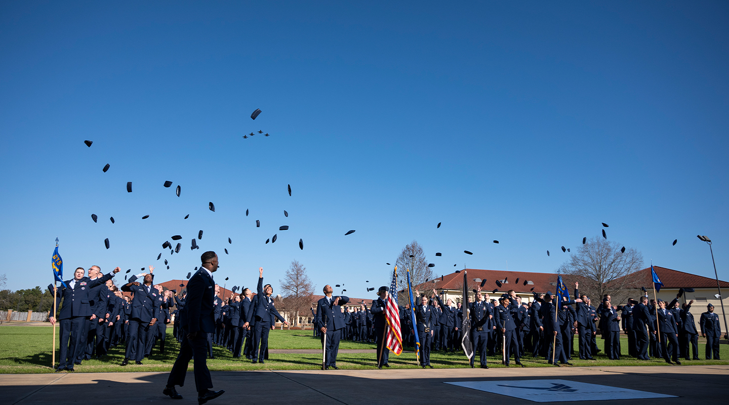 trainees throwing their cover in the air to celebrate their graduation