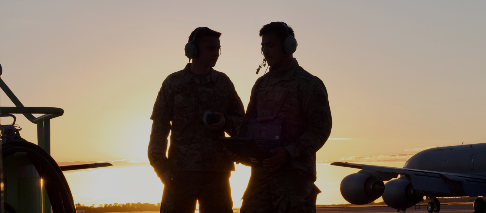 silhouette of two airmen talking to each other with the sun rising in the background