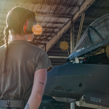 female airman wearing headphones looking at the aircraft