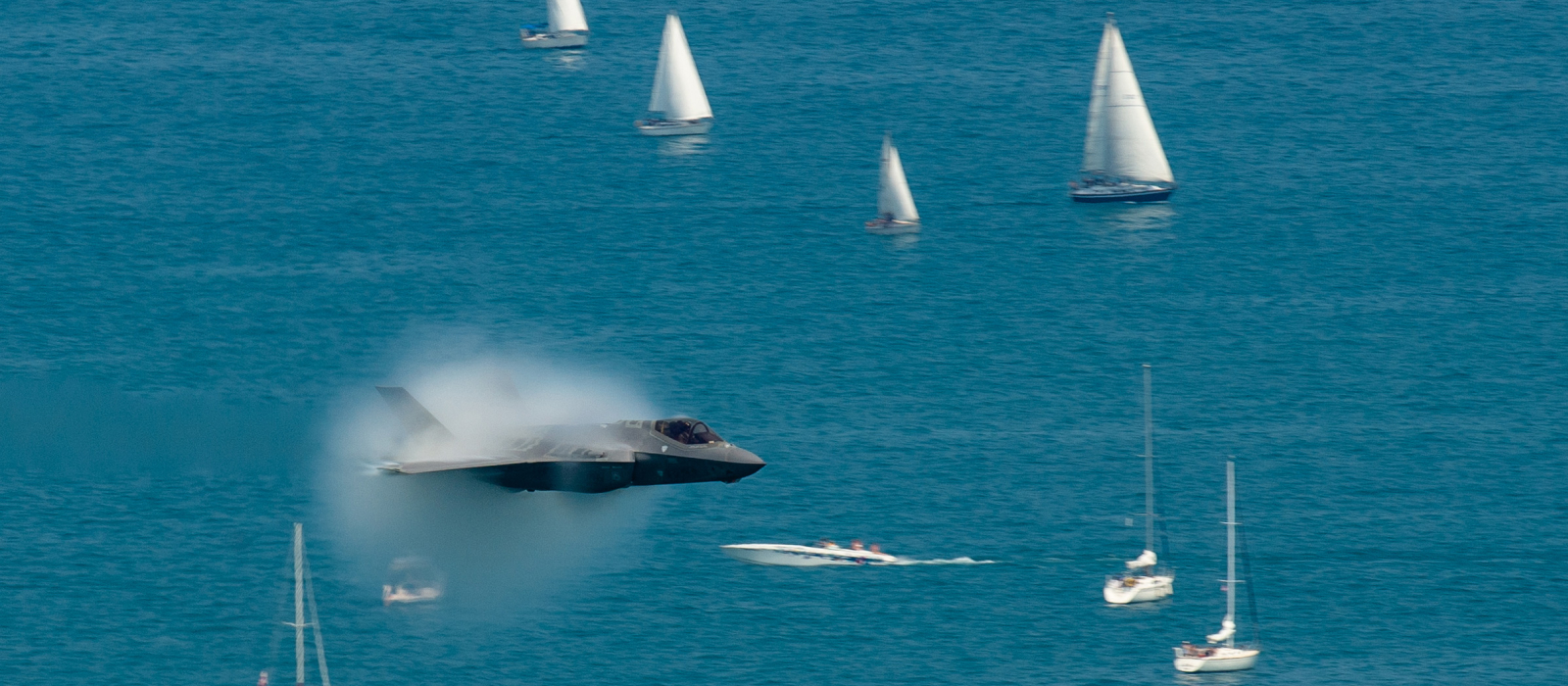 Fighter jet creating a sonic boom over water